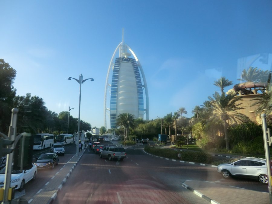 Burj Al Arab hinter einer Straße mit Verkehr und Palmen in Dubai