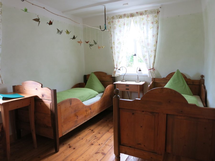 Hotelzimmer mit zwei Holzbetten und Schreibtisch